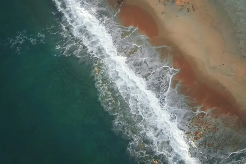 Captivating aerial view of waves crashing on Terengganu's sandy coast.